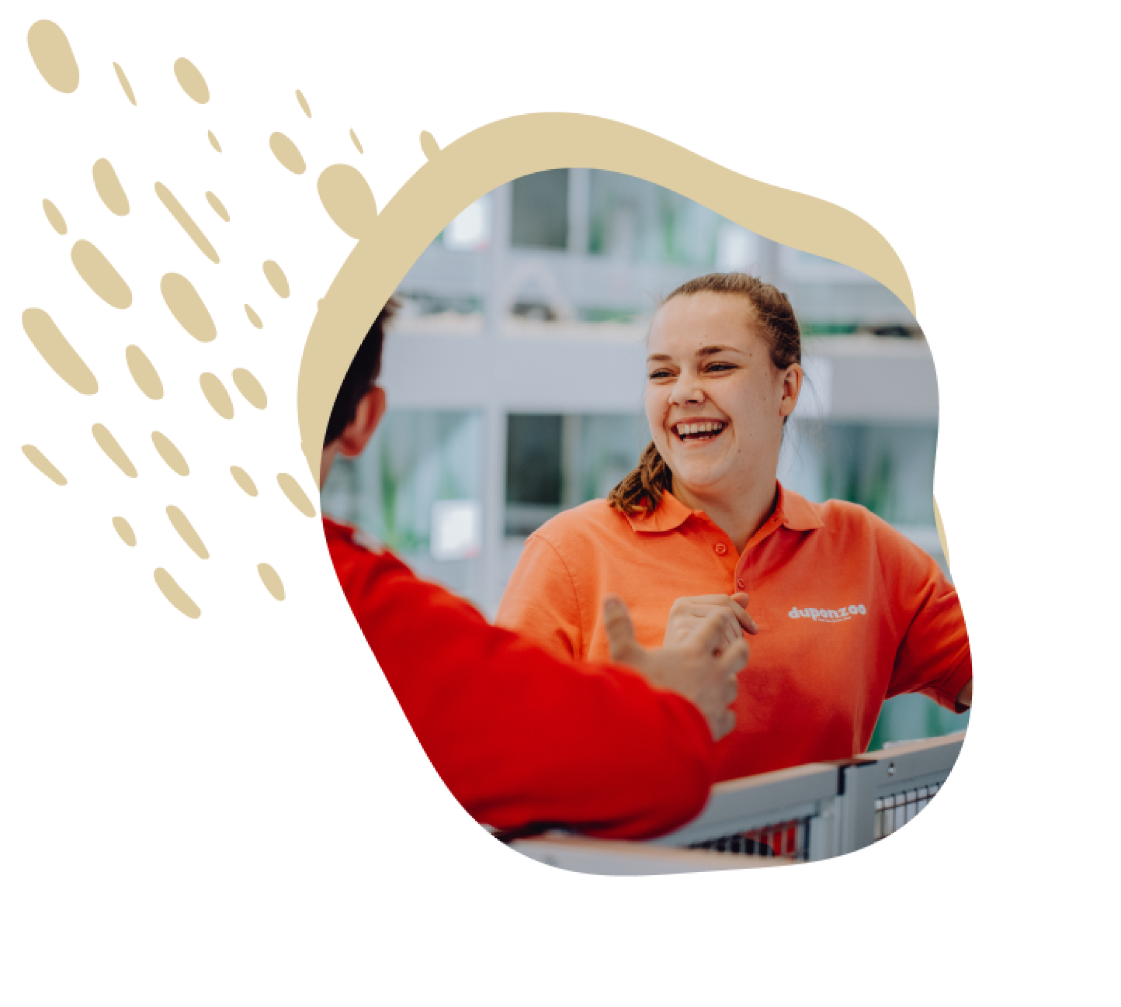 Een medewerkster van Duponzoo met een oranje polo staat iemand glimlachend te woord.